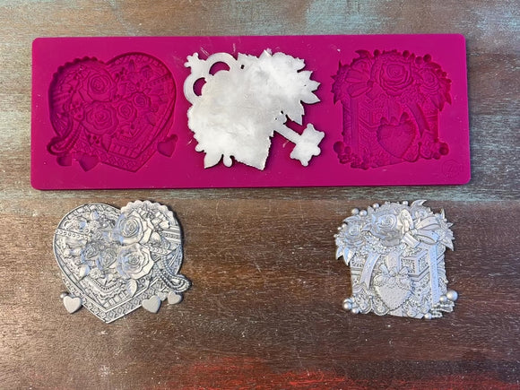 A 13 second video of Zuri Design's Valentine's Gifts silicone mold and silver colored castings are against a wood background. A hand is shown holding one of the castings.