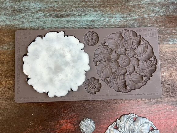 A 14 second video shows a close-up of ReDesign with Prima's Kacha Engraved Medallion brown silicone mold and silver colored castings. A hand is shown picking up one of the large floral medallion castings.