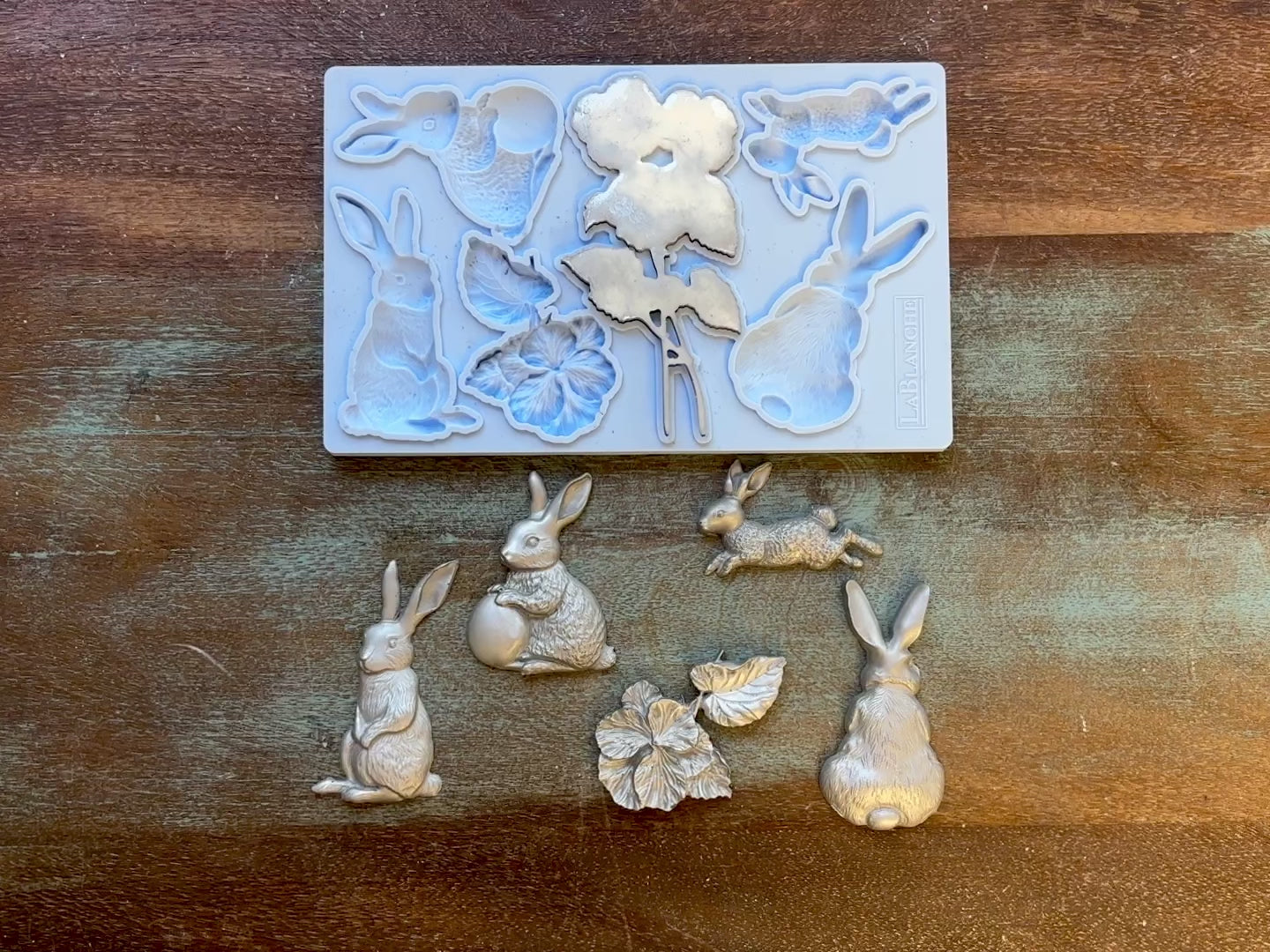 A 16 second video shows a close-up of LaBlanche's Easter Bunnies silicone mold and silver colored castings against a wood background. A hand is shown picking up one of the castings.