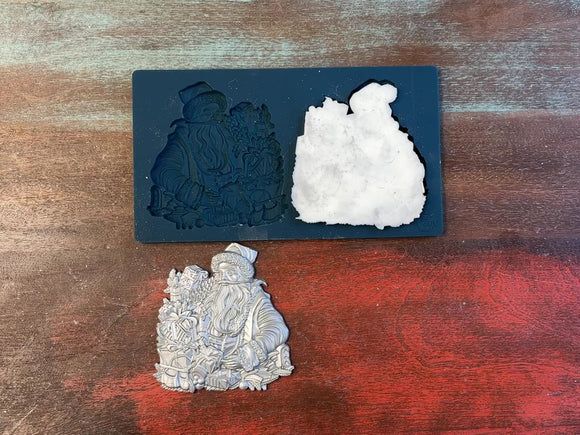 A 15 second video of Zuri Design's Father Christmas is against a wood background. A hand is shown holding one of the castings.