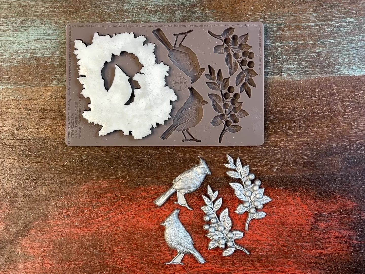 A 14 second video shows a close-up ReDesign with Prima's Cardinal Cheer silicone mold and silver colored castings. A hand is shown holding one of the castings.