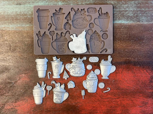 A 14 second video shows a close-up ReDesign with Prima's Cheerful Cups silicone mold and silver colored castings. A hand is shown holding one of the castings.