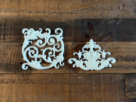 An 11 second video shows a close-up of white resin castings created from LaBlanche's Ornament Claudette silicone mold against a wood background. A hand is shown picking up and turning over one of the castings.