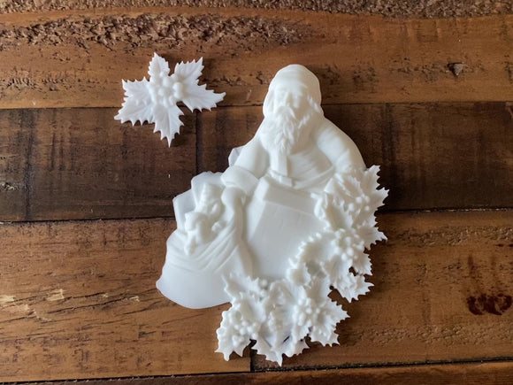 A 14 second video shows a close-up of white resin castings made from LaBlanche's St Nikolaus silicone mold against a dark wood background. A hand picks up and hold and turns over the Santa casting.