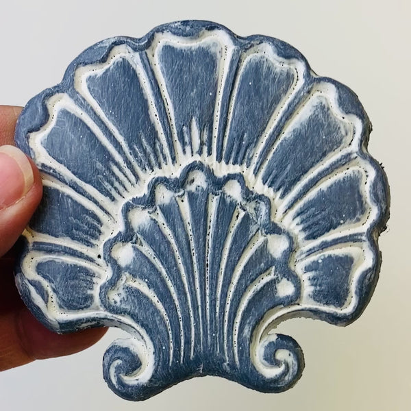 A 7 second video is shown holding a blue shell shaped flower silicone mold casting that has been detailed with Dixie Belle's White Wash Glaze.
