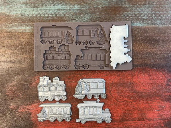 A 12 second video shows a close-up ReDesign with Prima's The Jolly Express silicone mold and silver colored castings. A hand is shown holding one of the castings.