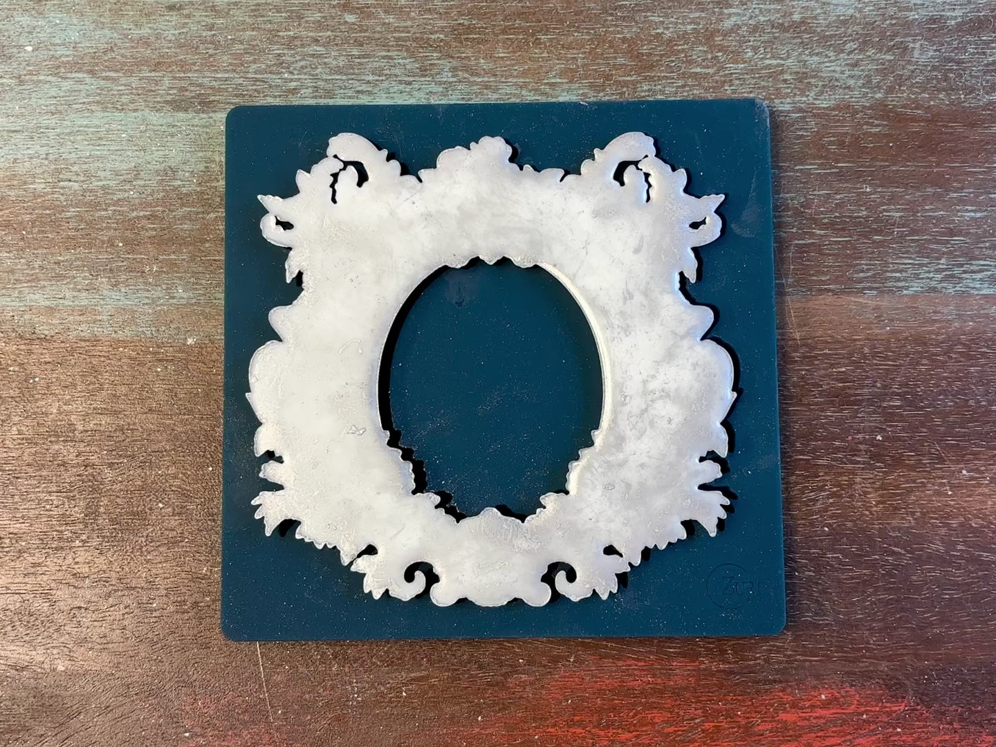 An 11 second video shows a close-up of Zuri Design's Oval Floral Frame against a wood background. A hand is shown lifting and holding the casting.