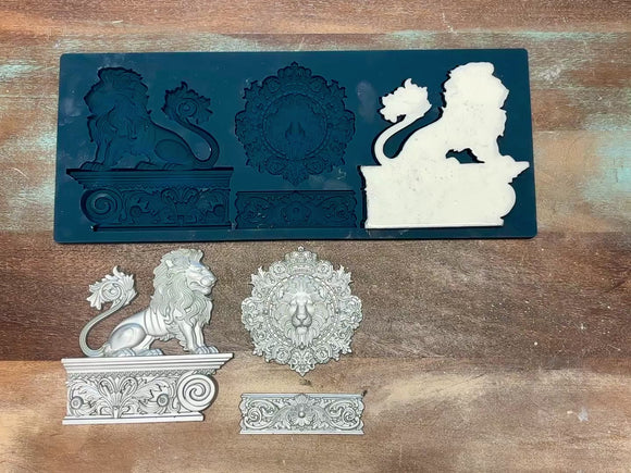 A 15 second video shows a close-up of Zuri's Baroque Lions silicone mold and silver colored castings against a wood background. A hand is shown picking up one of the lion statue castings.