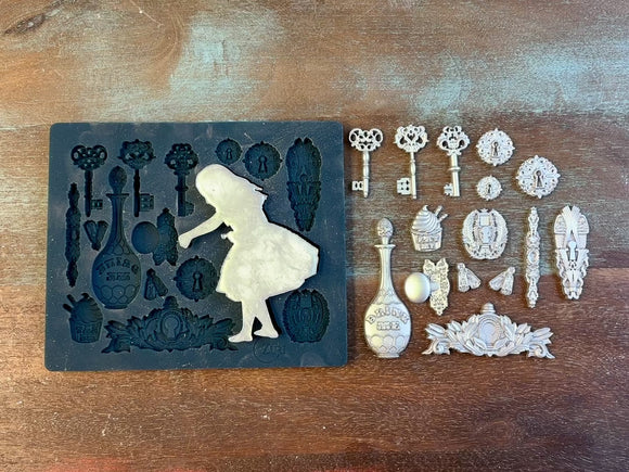 A 12 second video of Zuri Design's Alice's Keys silicone mold and silver colored castings are against a wood background. A hand is shown holding the Alice casting.