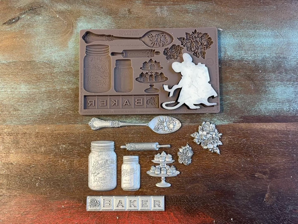 A 15 second video of Prima Marketing's Baker's Delight silicone mold and silver colored castings are against a wood background. A hand is shown holding the mouse casting.