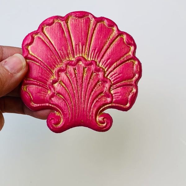 A 7 second video is shown holding a red shell shaped flower silicone mold casting that has been detailed with Dixie Belle's Gold Glaze.