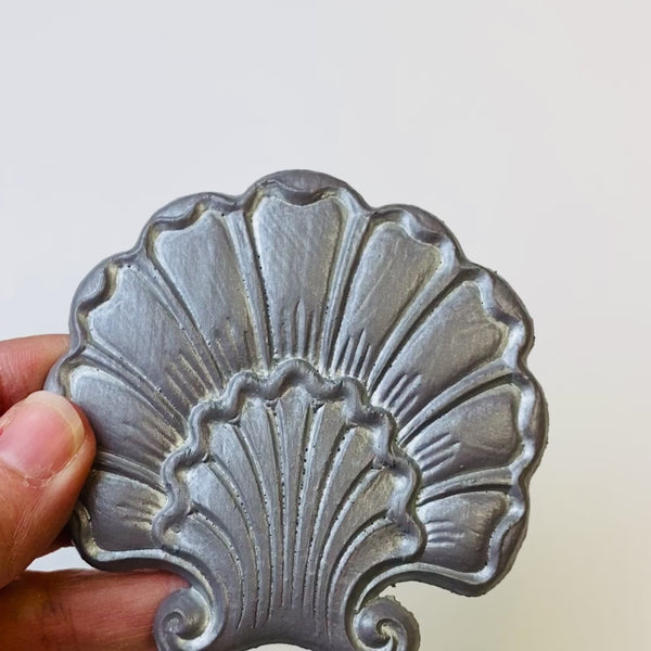 A 7 second video is shown holding a grey shell shaped flower silicone mold casting that has been detailed with Dixie Belle's Silver Glaze.