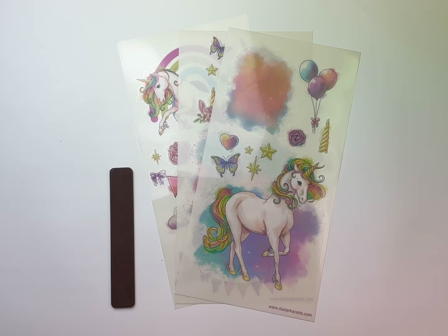 A 15 second video shows a close-up and backside of three sheets of Dadarkar Art's Dear Unicorn small rub-on transfers against a white background.