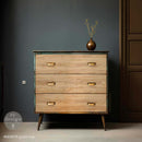 A mid-century dresser is painted a rusty patina green and features ReDesign with Prima's Grain Hue A1 fiber paper on its 3 drawers.