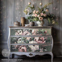 A vintage dresser is painted a distressed grey and features ReDesign with Prima's Mossy Rose Delight A1 fiber paper on its 3 large drawers.