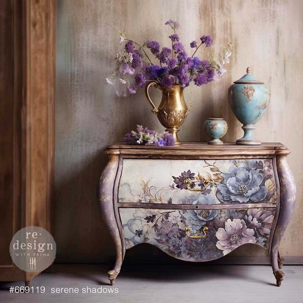 A vintage nightstand is painted soft lavender and features ReDesign with Prima's Serene Shadows A1 fiber paper on its 2 drawers.