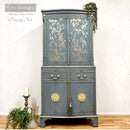 A tall armoir refurbished by Bozenka Art, a ReDesign Brand Ambasador, is painted a grey-blue and features A Bird Song on its doors.