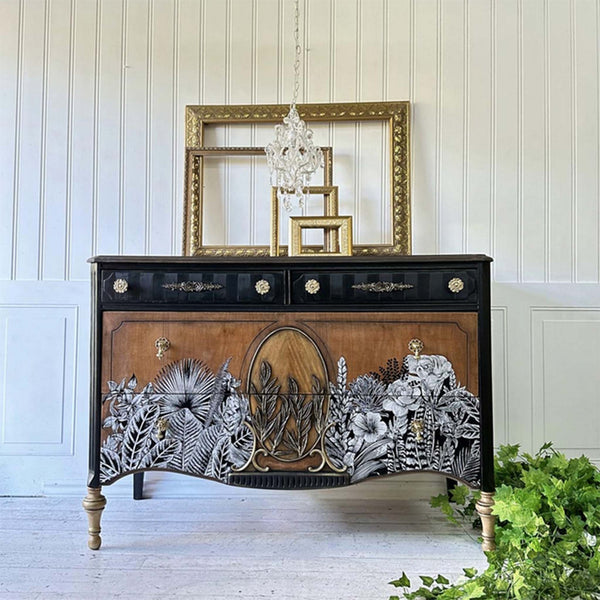 A vintage dresser is painted black with a natural wood stain and features the Abstract Jungle transfer on its drawers.
