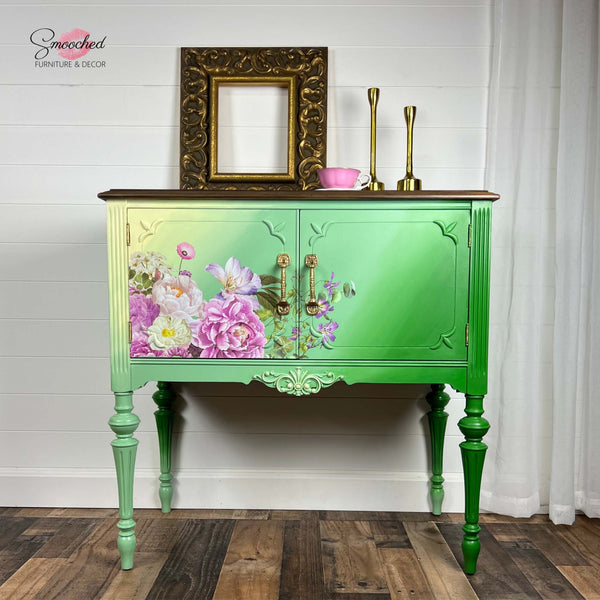A vintage side table with storage refurbished by Smooched Furniture Decor is painted a blend of bright greens and pale yellow and features the Kacha Morning Purple transfer on its doors.