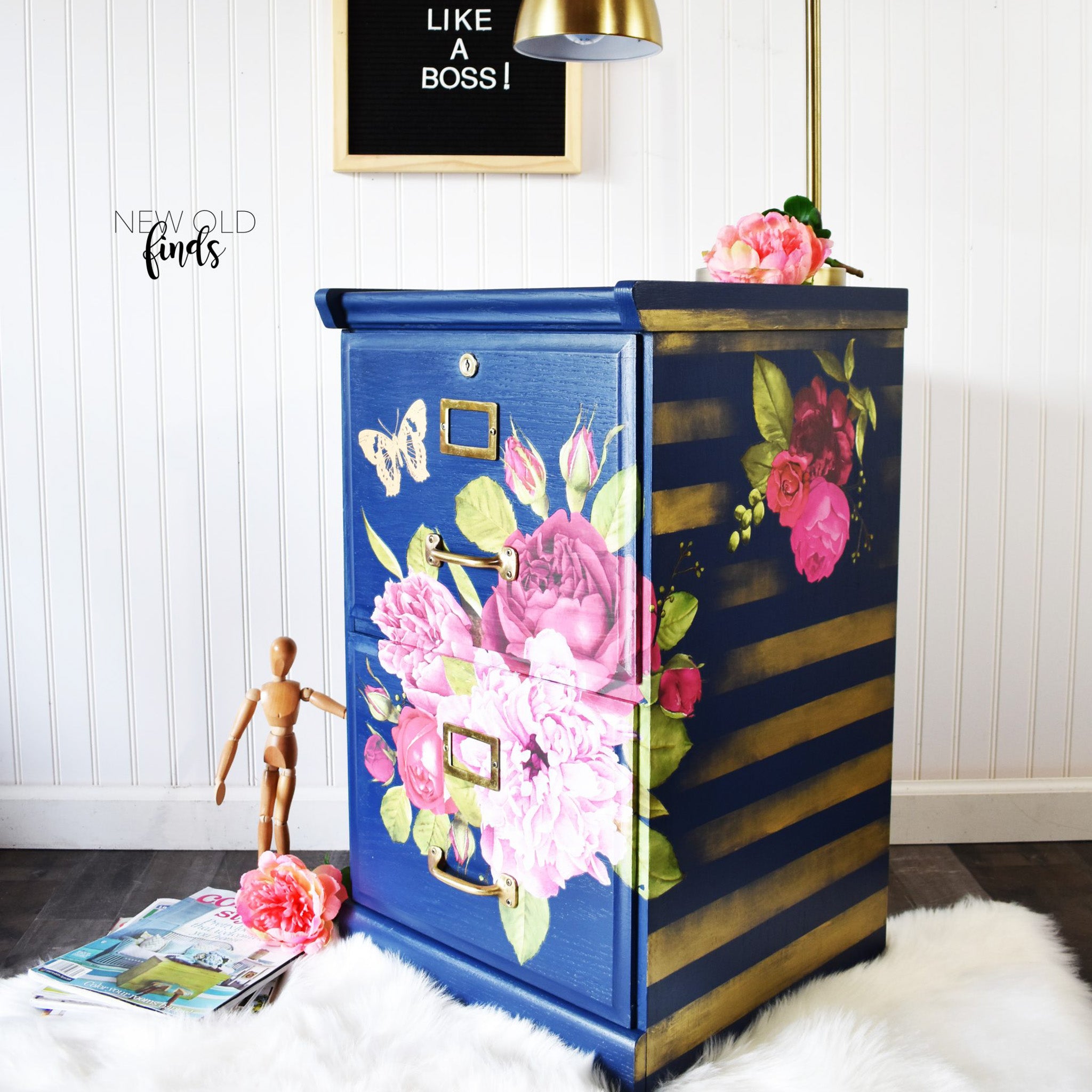 A vintage 2-drawer file cabinet refurbished by New Old Finds is painted navy blue with gold stripes on the sides and features ReDesign with Prima's Lush Floral 1 rub on transfer on the front and side.