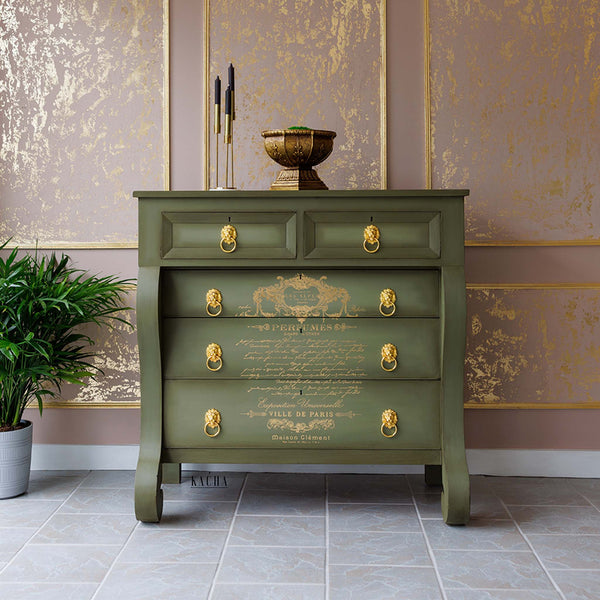 A 5-drawer dresser refurbished by Kacha is painted a sage green with gold hardware and features Perfume Notes on its drawers.