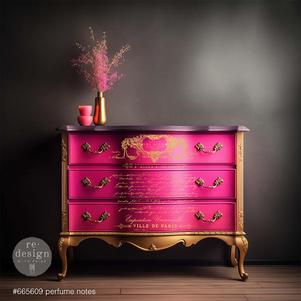 A French Provencial 3-drawer dresser refurbished by ReDesign with Prima is painted pink and gold and features Perfume Notes on its drawers.