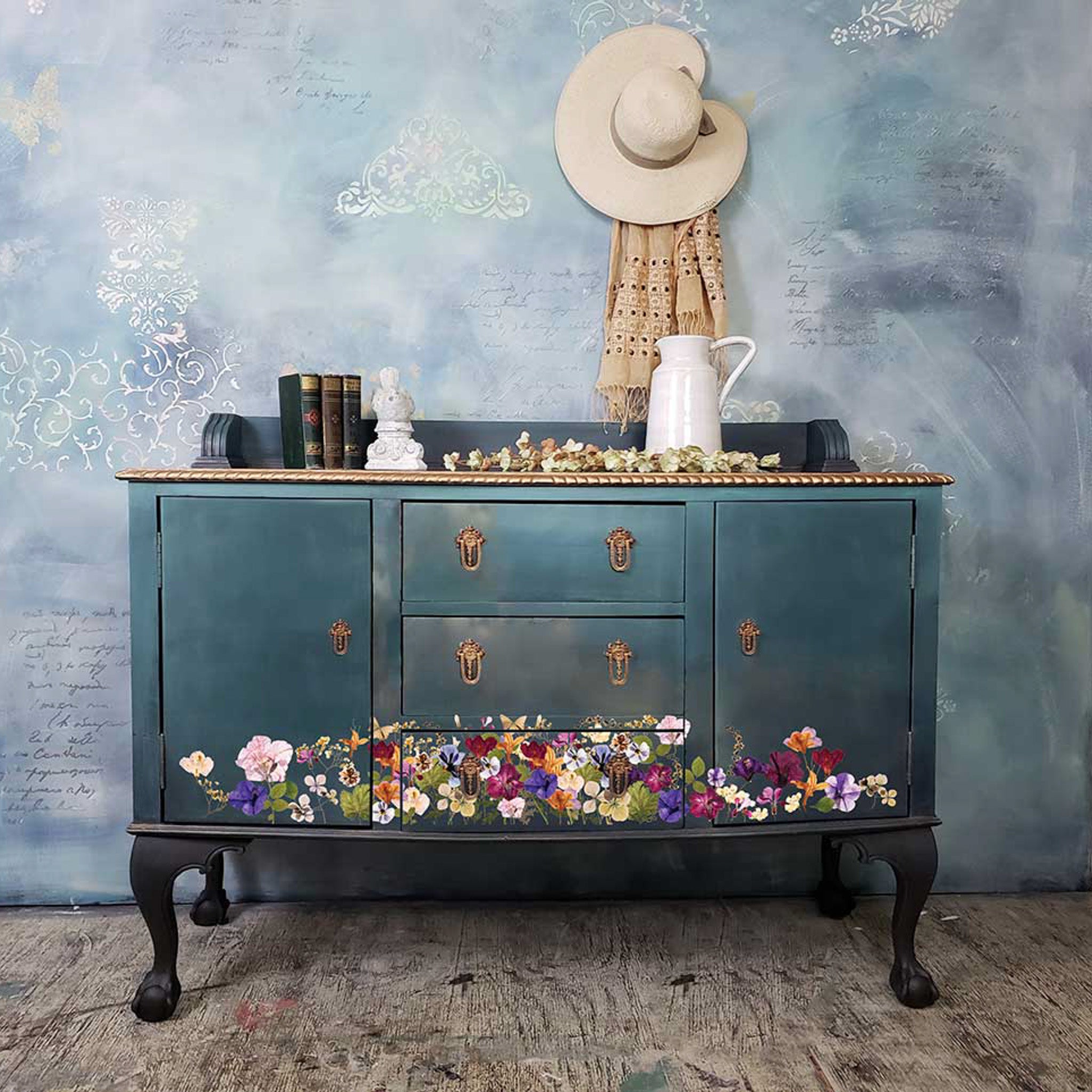 A vintage buffet console table is painted a dark mottled teal and features ReDesign with Prima's Pressed Flowers transfer across the front bottom.