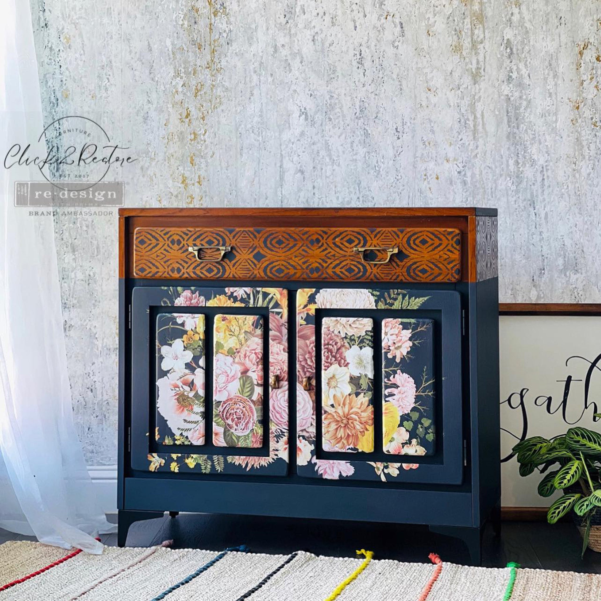 A vintage small buffet cabinet refurbished by Click 2 Restore is painted navy blue with natural wood accents and features ReDesign with Prima's Kacha Wooland Floral transfer on its 2 doors.