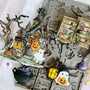 Halloween-themed miniature scene with haunted house, ghosts, and books on a textured surface.