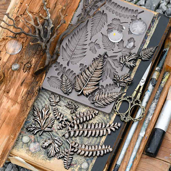 Silicone leaf mold on a textured surface with tools and natural elements.