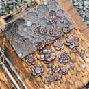 Metal flower-shaped mold on a wooden surface with metal flowers around it.