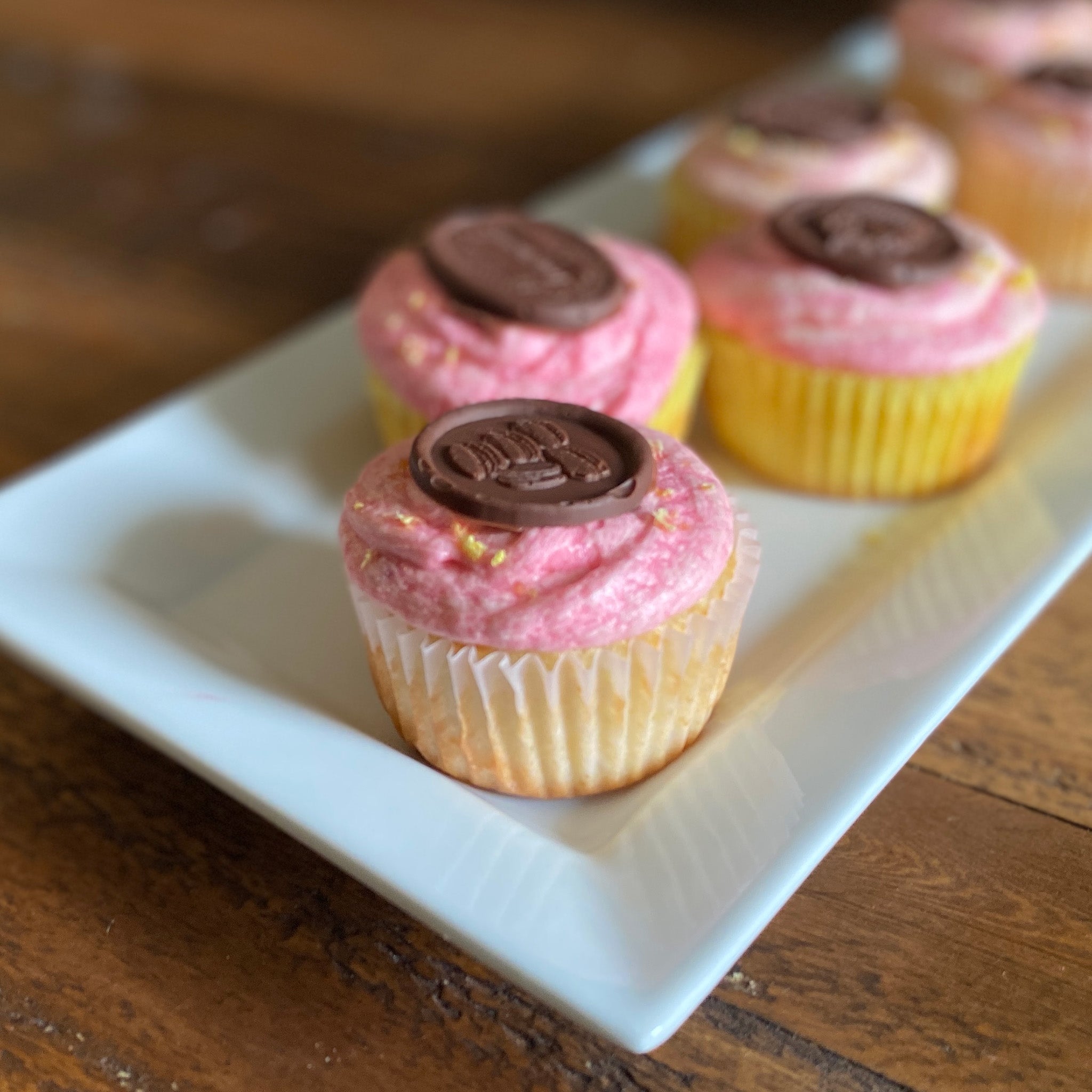 A tray of cupcakes feature milk chocolate castings made from Prima Marketing's Sweet Seal silicone mold.