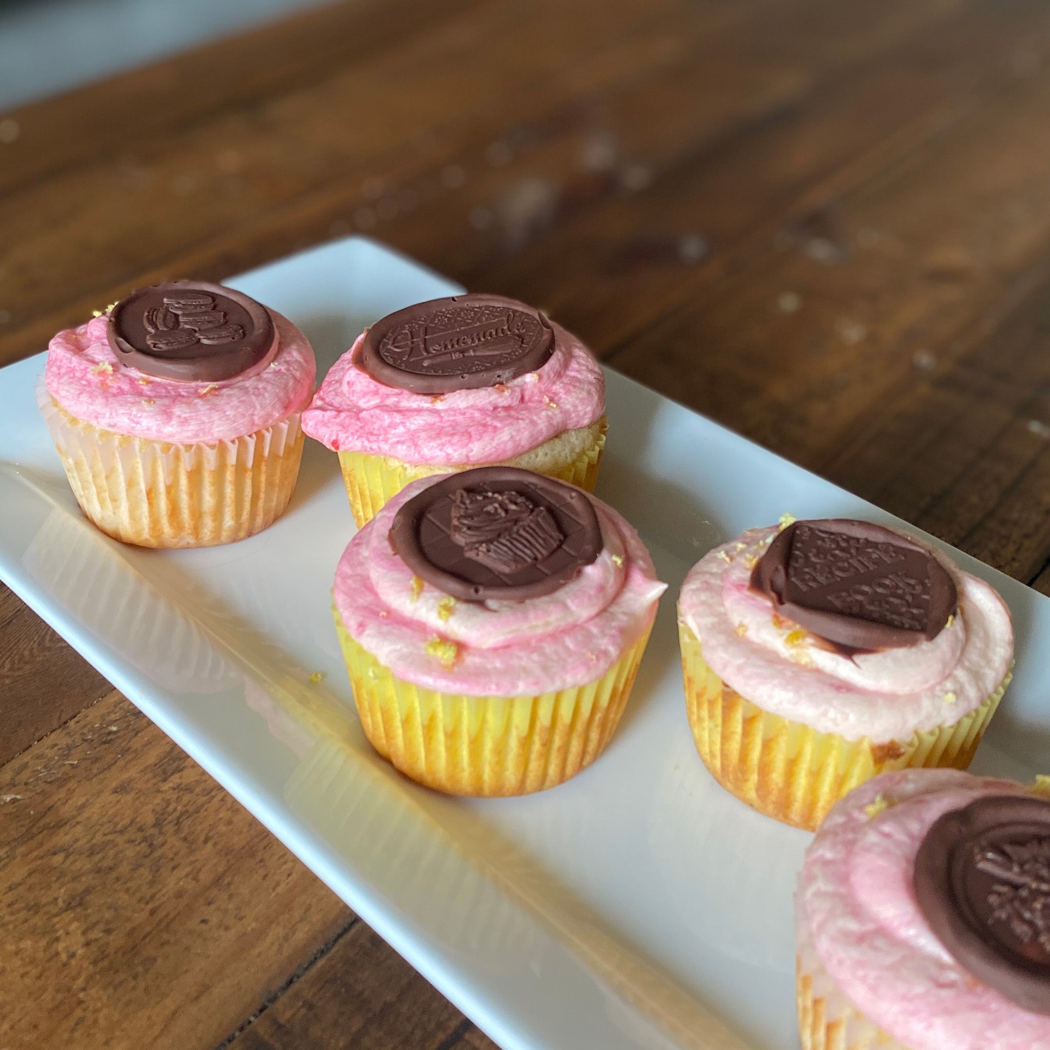 A tray of cupcakes feature milk chocolate castings made from Prima Marketing's Sweet Seal silicone mold.