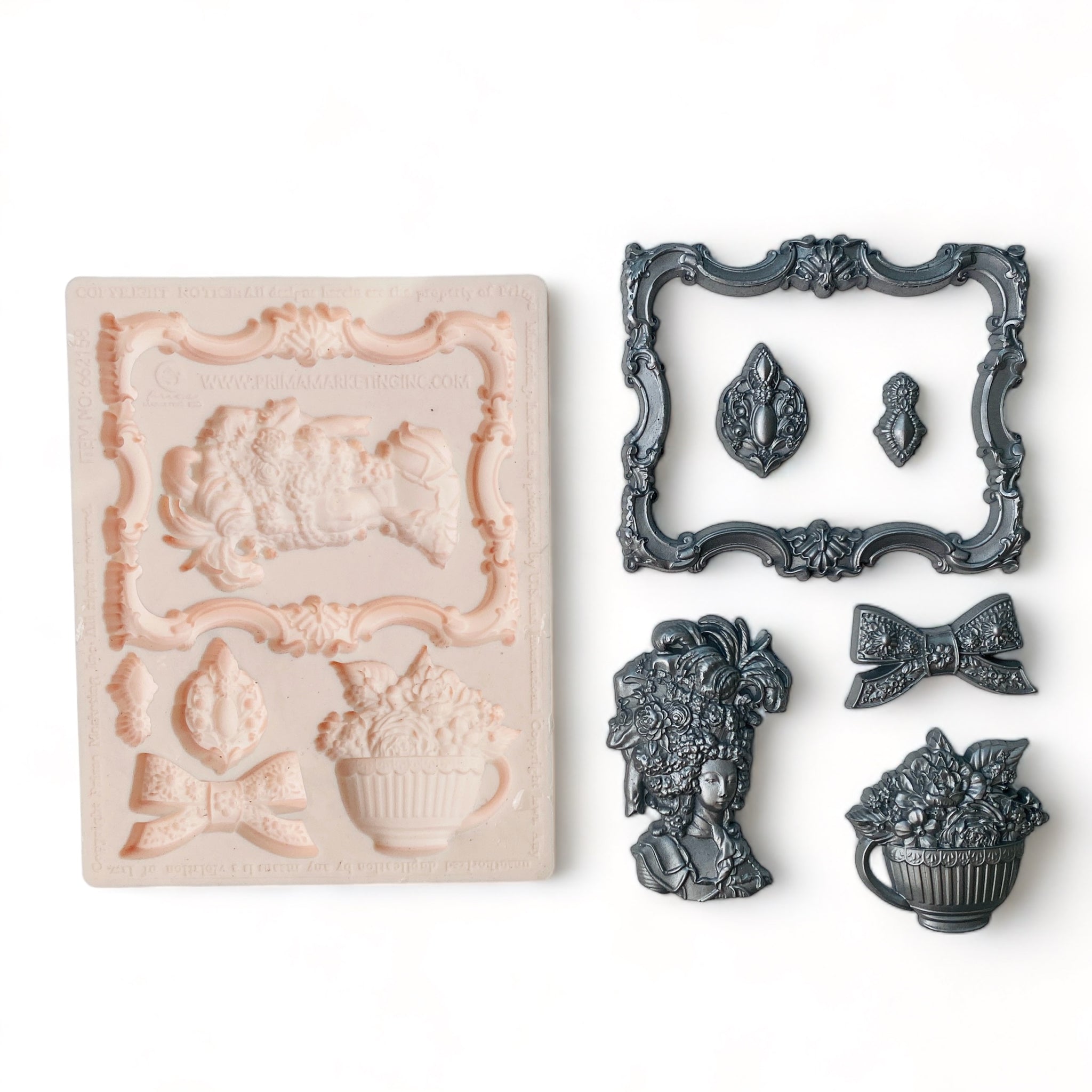 A beige silicone mold and silver colored castings of an ornate frame, ribbon bow, Marie Antoinette style head bust, bouquet of flowers in a large cup, and 2 small medallions are against a white background.