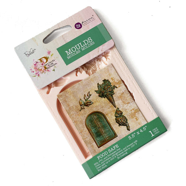 Silicone mould and its package of Prima's Postcards from Paradise is on a white background. The mould features a wood paned window, foliage, an owl, and a bouquet of flowers.