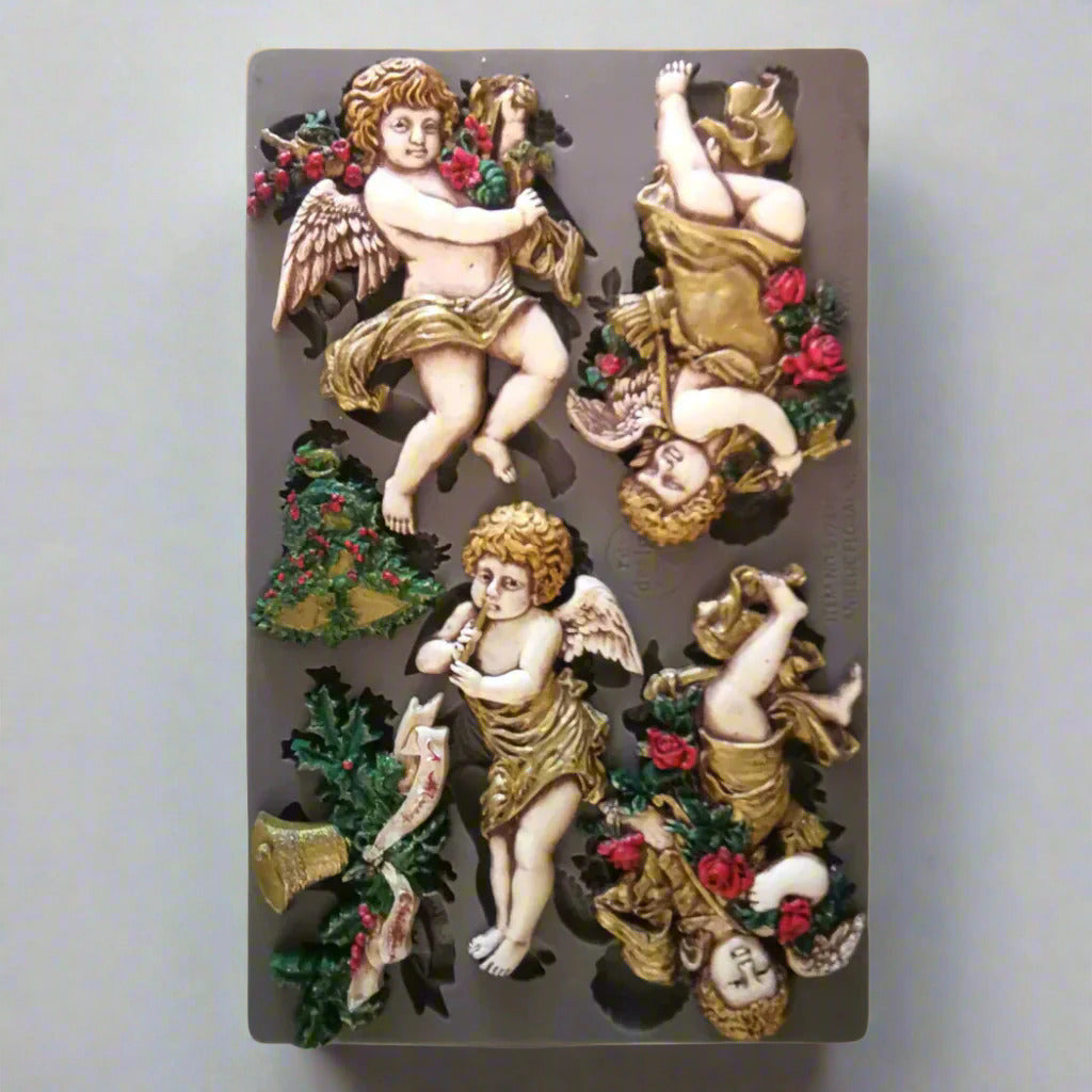 Decorative mold with angel figures and floral elements on a textured background