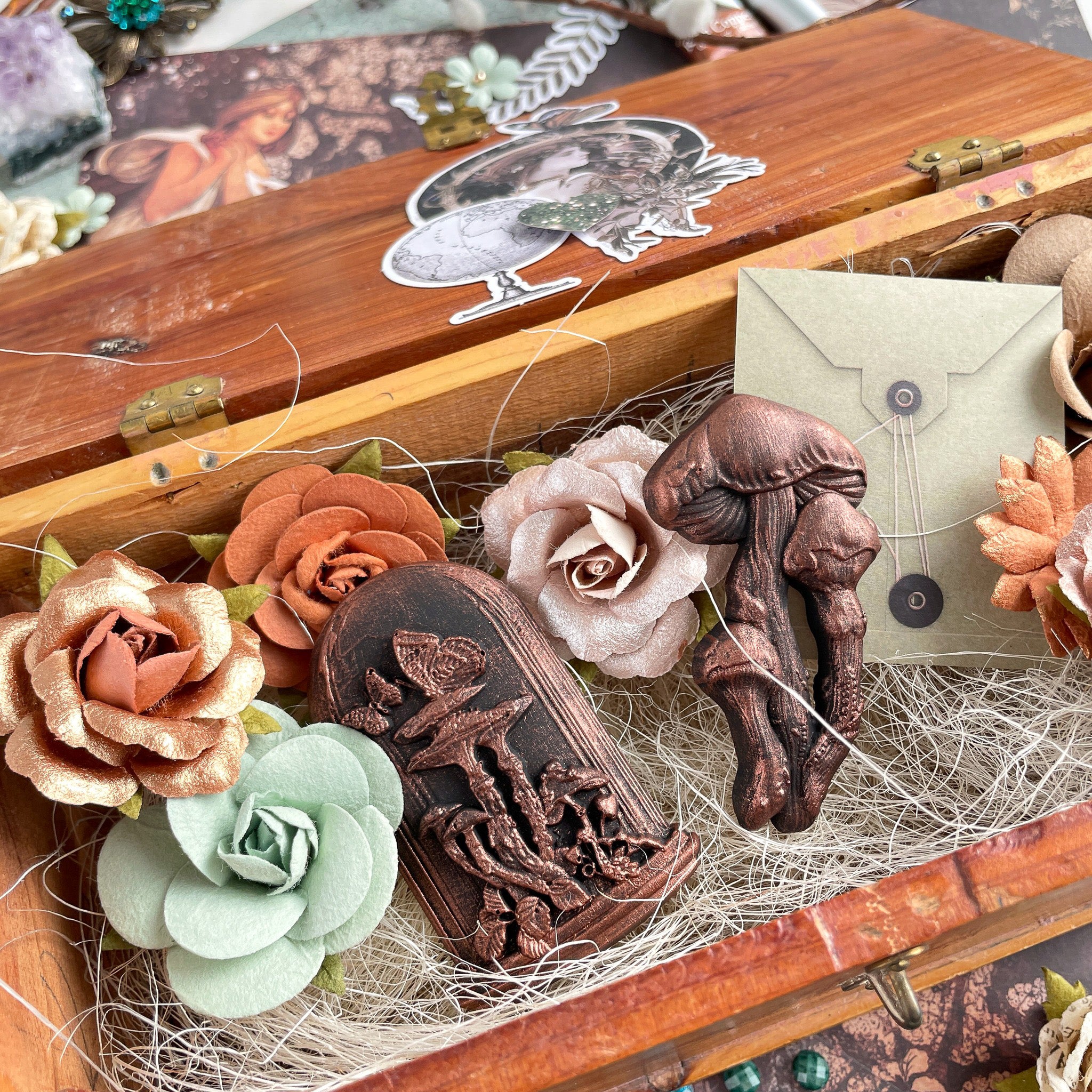 Bronze colored silicone mold castings from Prima Marketing's Nature Academia silicone mold are in a vintage box with straw and felt roses.