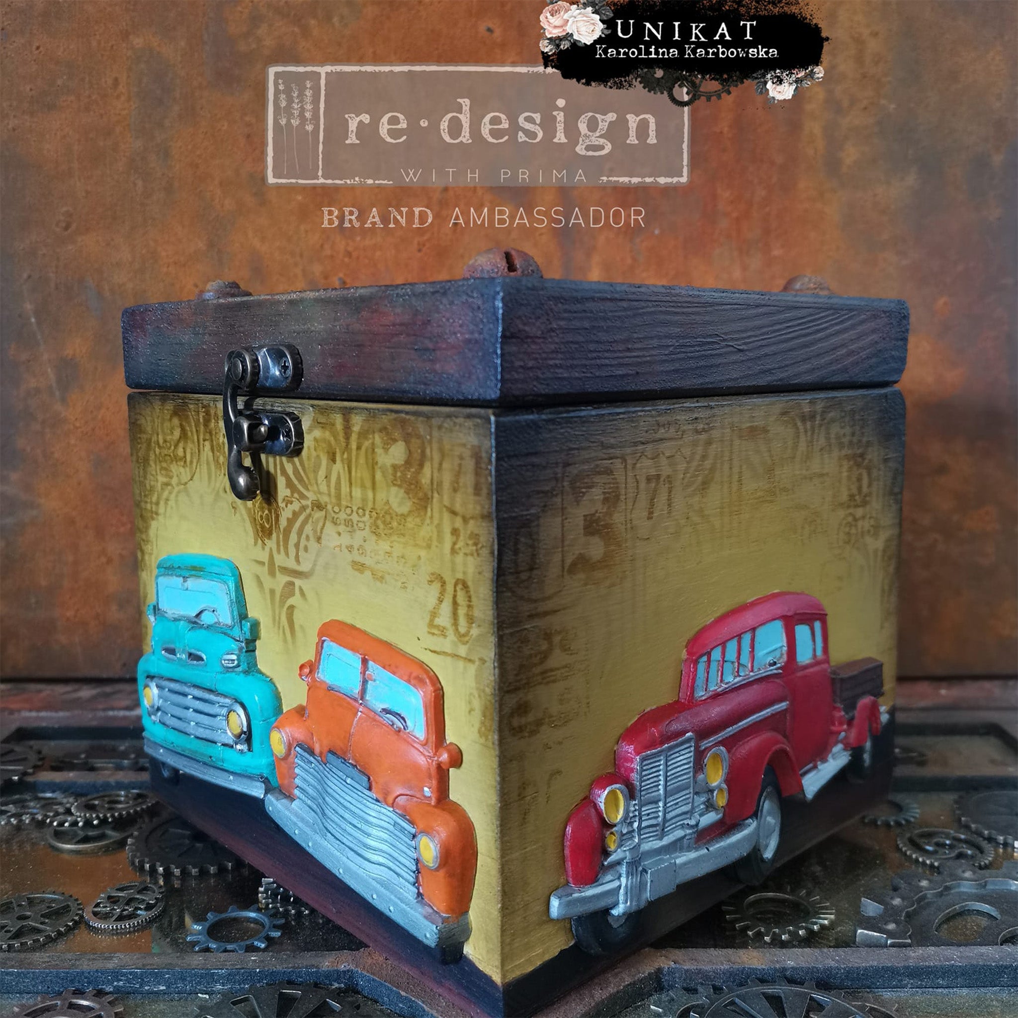 A small wood box refurbished by Unikat is painted pale yellow with a dark stain lid features colorful castings from ReDesign with Prima's Truck silicone mold on the sides.