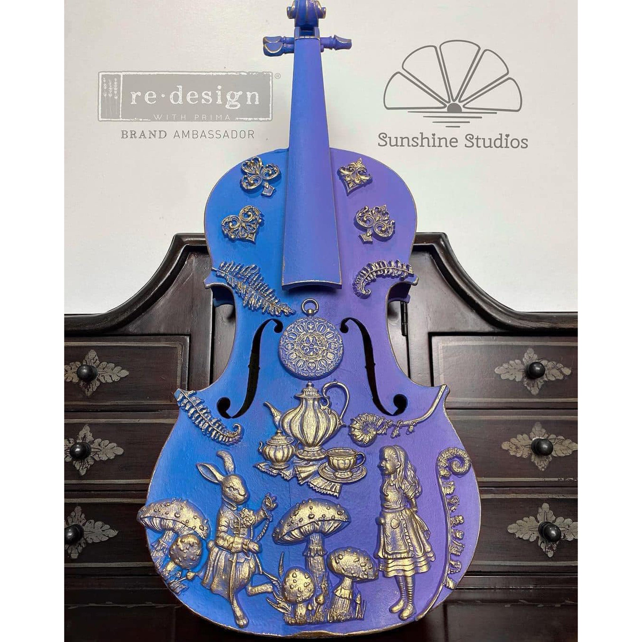 A violin refurbished by Sunshine Studios is painted blue and features silver colored castings of ReDesign with Prima's Following Alice silicone mold.