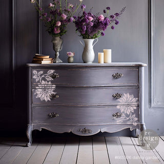 A vintage 3-drawer dresser is painted a light grey-purple and features the Dahia Garden mylar stencil on its drawers.