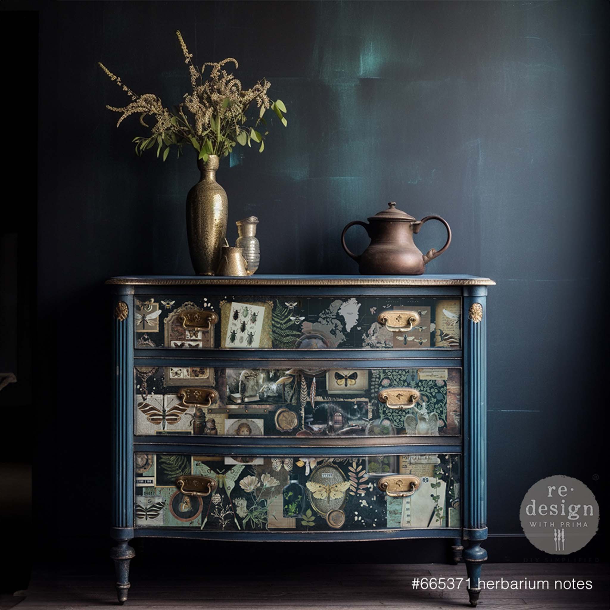 A dark blue 3-drawer side table repurposed by ReDesign with Prima is painted blue with gold accents and features Herbarium Notes on its drawers.