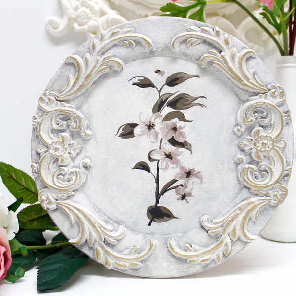 14" Paulownia Wood Charger is painted white with scrolling moulding on it and a transfer of flowers in the center.