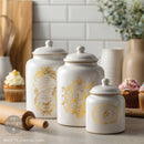White ceramic kitchen canisters decorated with Chant Du Matin gold water slide transfers featuring birds and French label designs