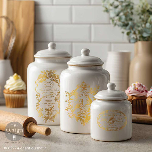 White ceramic kitchen canisters decorated with Chant Du Matin gold water slide transfers featuring birds and French label designs