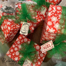 Christmas gifts wrapped in red paper with white snowflakes created by Reimaginings Artisan Furniture feature gift tags created with ReDesign with Prima's Merry and Bright clear decor stamps.