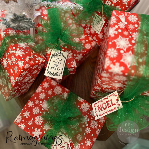 Christmas gifts wrapped in red paper with white snowflakes created by Reimaginings Artisan Furniture feature gift tags created with ReDesign with Prima's Merry and Bright clear decor stamps.
