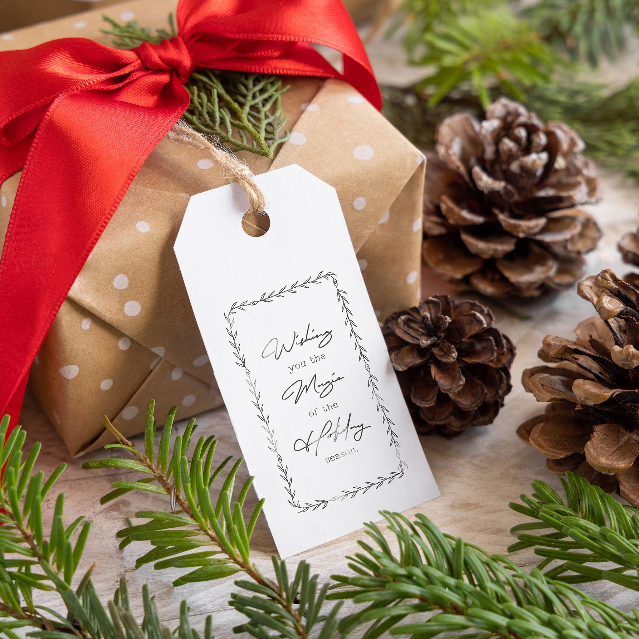 A brown paper wrapped gift has a white gift tag that features a stamp from ReDesign with Prima's Merry & Bright Decor Stamp.