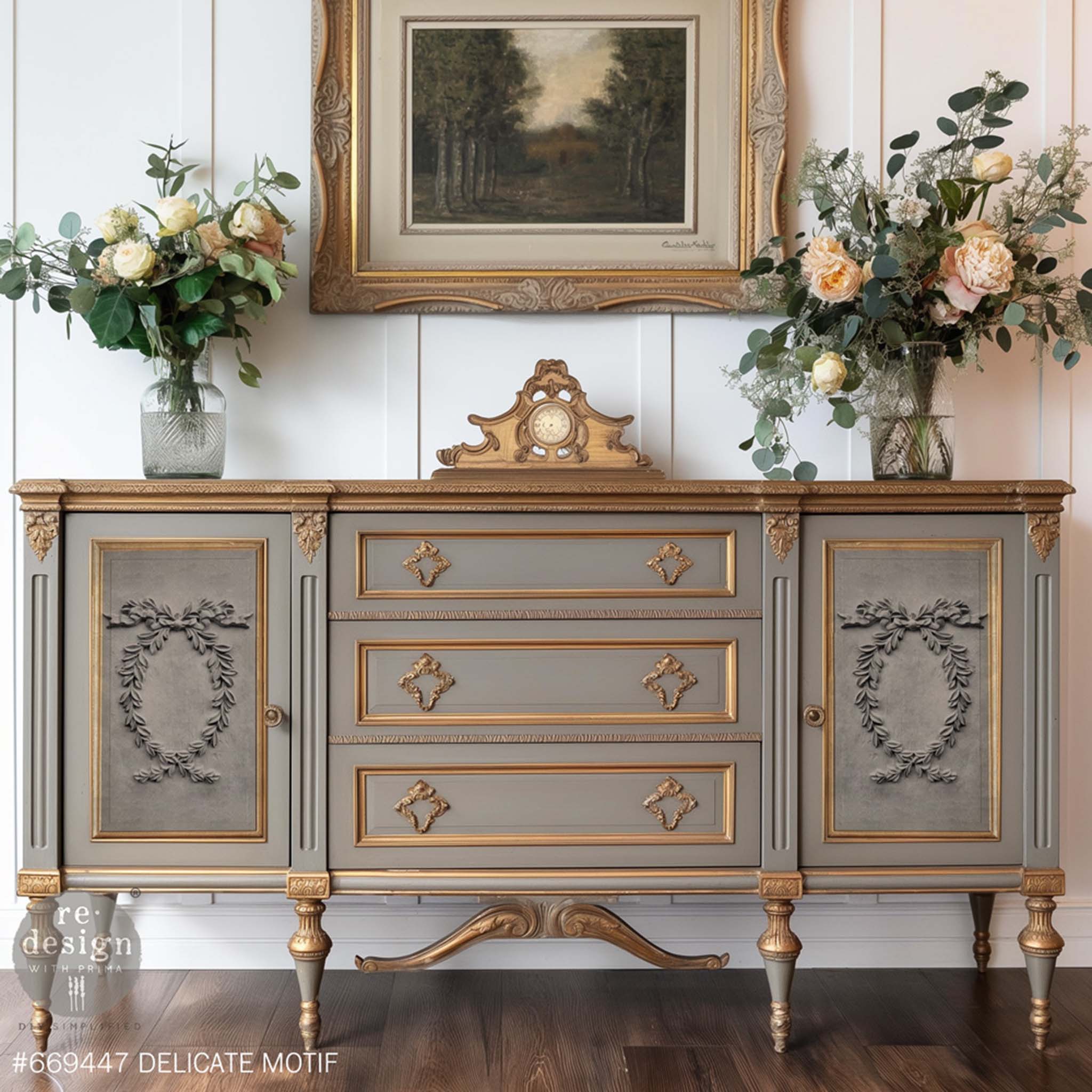 A vintage console table with drawers and doors is painted a warm gray with bronze accents and features ReDesign with Prima's Delicate Motif Decor Poly Casting bendable furniture appliques on the 2 doors.