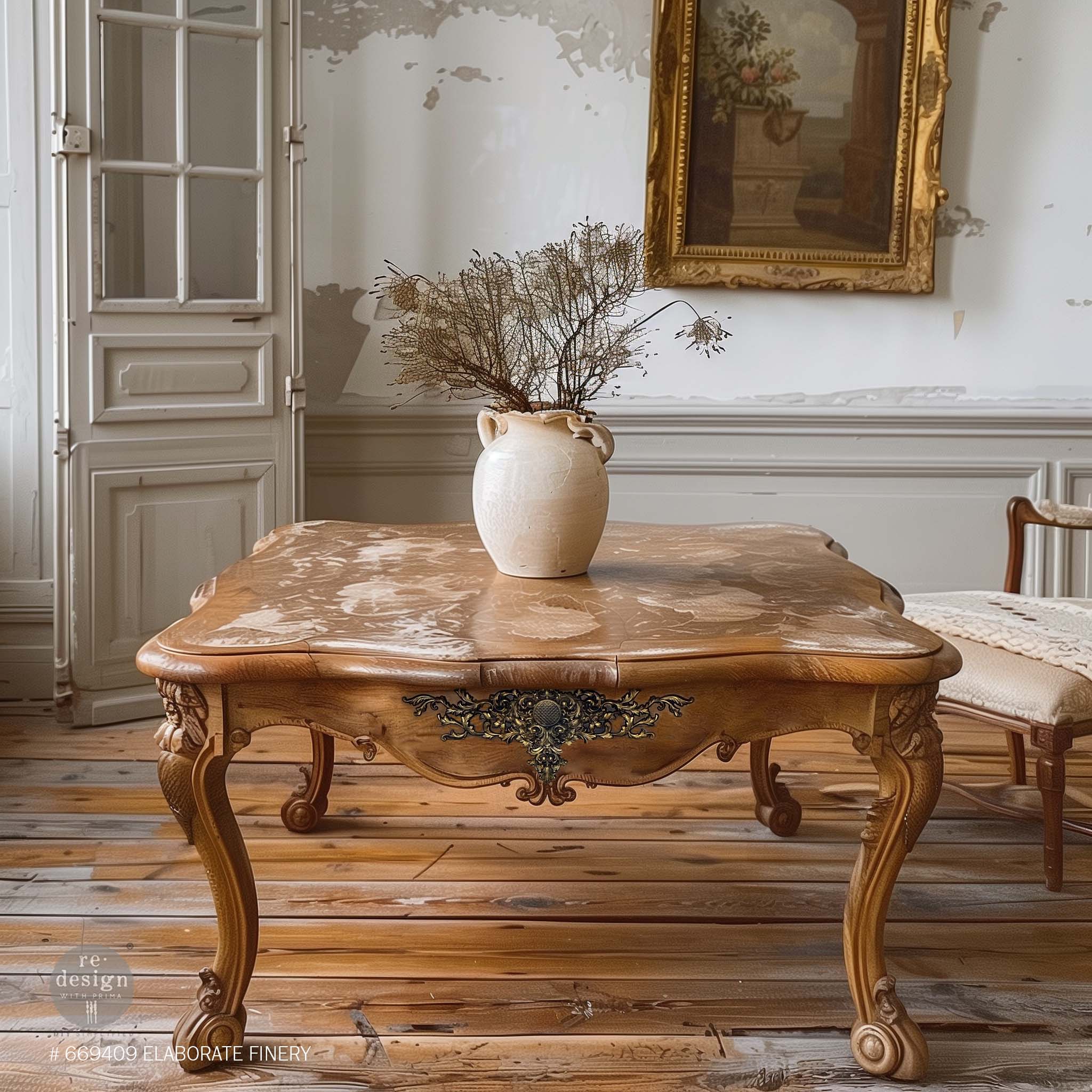 A vintage kitchen table is natural wood and features ReDesign with Prima's Elaborate Finery Decor Poly Casting on a side panel.
