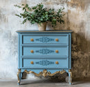 A vintage 3-drawer dresser is painted light blue with gold accents and features ReDesign with Prima's Luxe Ornamenta Decor Poly Casting in the center of its drawers.